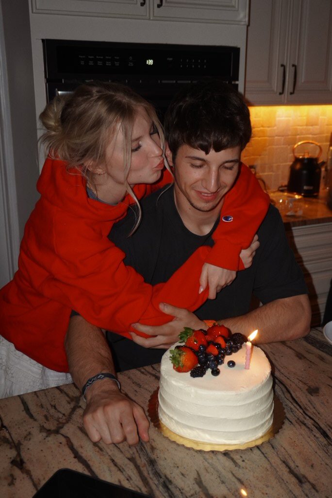 Francesca kissing Simon as he sits behind a birthday cake