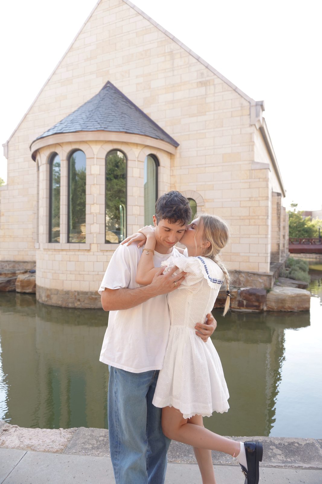 Francesca kissing Simon beside a stone chapel