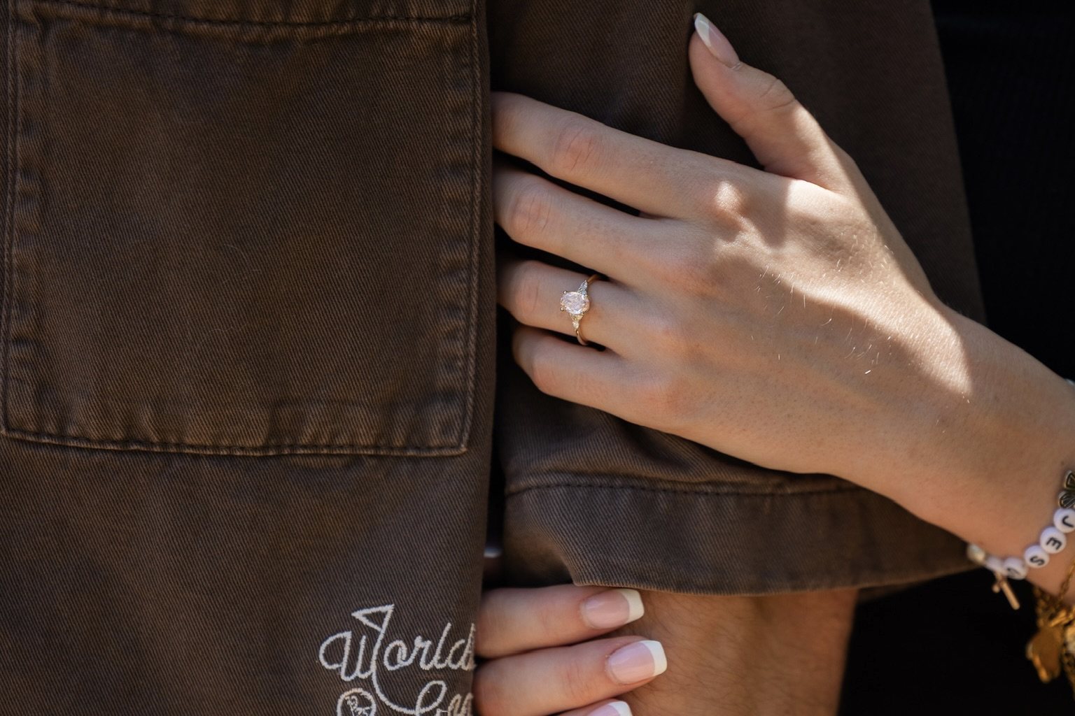 Francesca's hand wearing her engagement ring, resting on Simon's arm