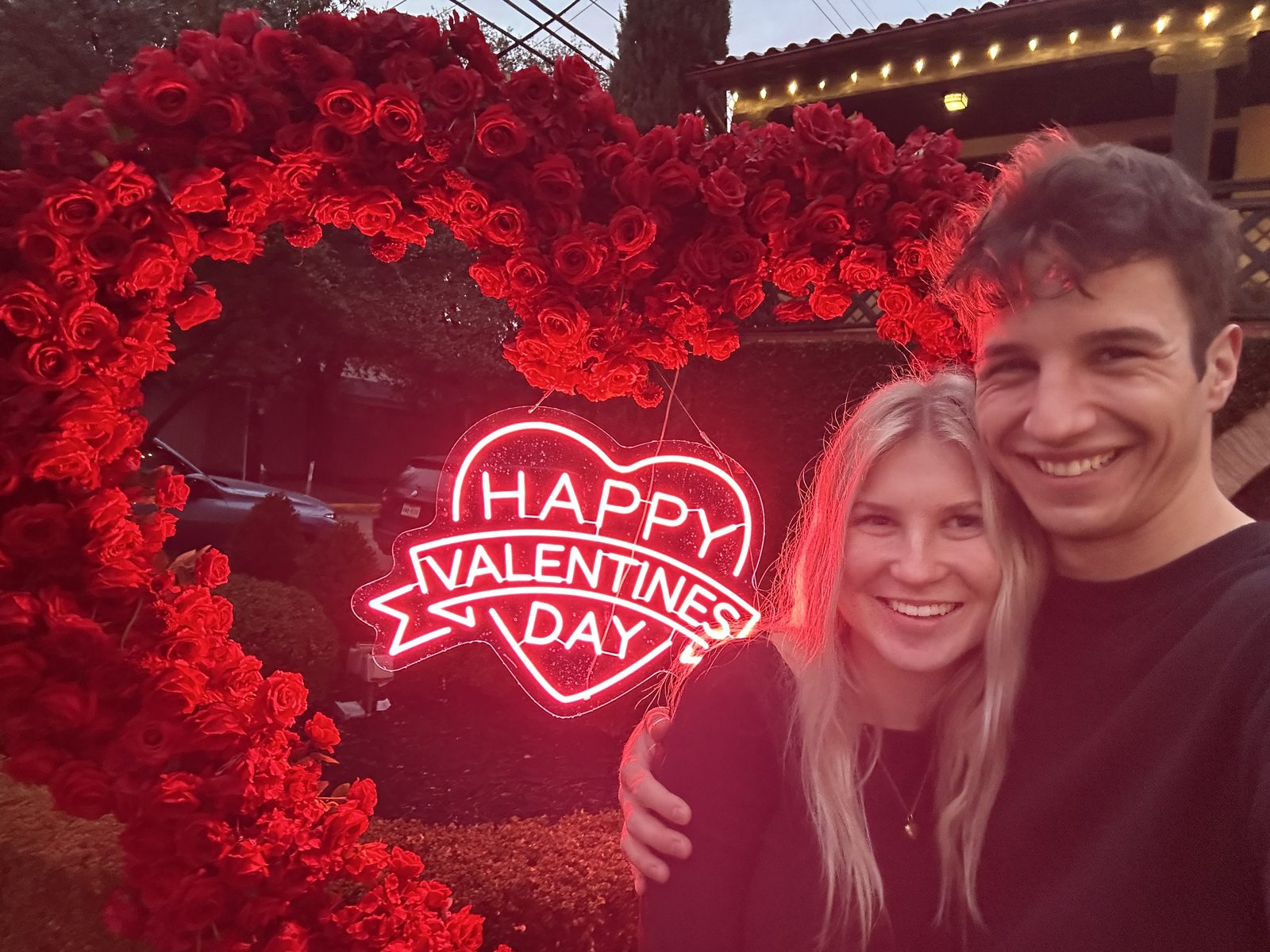 Simon and Francesca in front of a heart of red roses on Valentine's Day